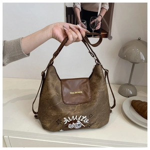 Dettaglio della borsa vintage in pelle marrone con stampa retrò e tracolla regolabile