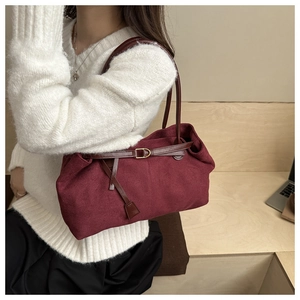 Detail of burgundy faux suede tote bag featuring brown leather straps and metal buckle accent