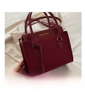 Détail du sac à main bordeaux en cuir avec textures mixtes et texte doré élégant
