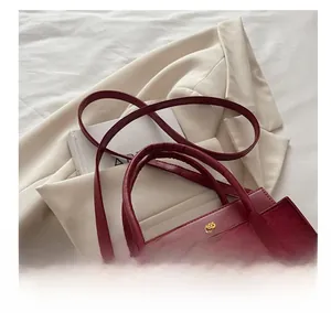 Détails du cuir rouge texturé avec épissage et lettrage doré sur ce sac à main chic