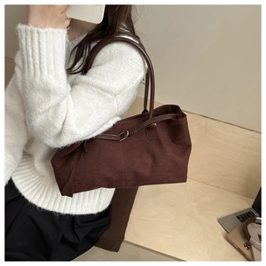 Close-up of dark brown suede tote bag with fine stitching and metallic buckle detail