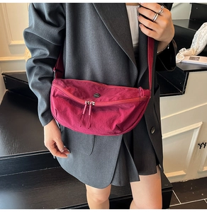 Close-up of burgundy oxford nylon crescent bag with double zipper and black logo
