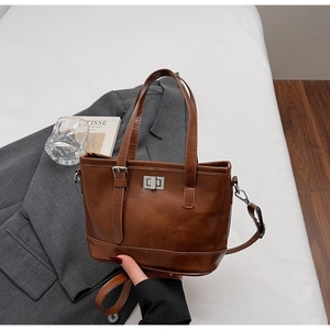 Détail d'un sac cabas vintage en cuir marron avec fermoir argenté sur un costume