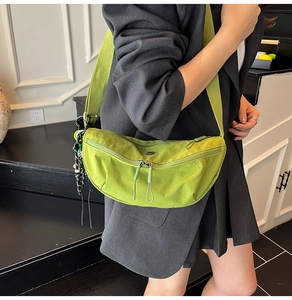 Model wearing a grass green Oxford crescent crossbody bag with checkered charm accessory