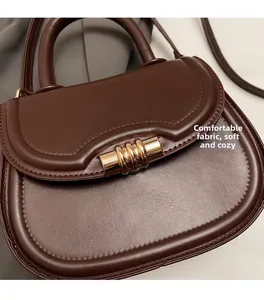 Détail macro du sac besace marron foncé avec boucle métallique et texture en cuir souple