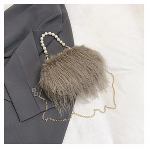 Dettaglio borsa di peluche marrone con manico di perle e catena in metallo su tessuto