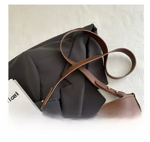 Détail de la bandoulière en cuir marron avec rivets dorés et boucle de réglage en métal