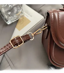 Vue détaillée du sac en cuir marron foncé montrant les ferrures dorées et les coutures