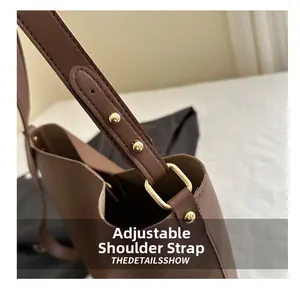 Détail d'une bandoulière réglable avec boucle dorée sur un sac en cuir marron foncé