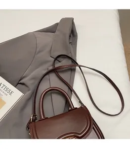 Détail de la bandoulière réglable et des finitions dorées du sac selle marron