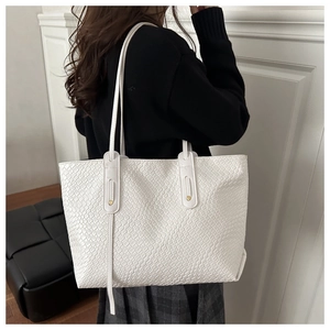 Detail of off-white woven tote bag with leather straps and gold rivets for women