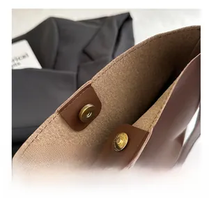Détail d'un sac cabas en cuir marron avec fermoir magnétique doré et doublure en feutre