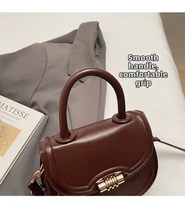 Détail de la poignée ronde et du fermoir spirale doré sur le sac en cuir marron foncé
