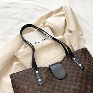 Detailed view of large coffee tote bag with M-pattern and black leather strap