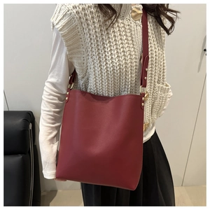 Détail du sac seau en cuir bordeaux avec rivets métalliques et bandoulière réglable
