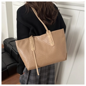 Detail of light beige tote bag with crocodile embossing and reinforced shoulder straps