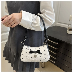 Détail du sac jacquard blanc à nœuds noirs et pendentif en forme de coeur