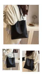 Détail du sac cabas en cuir noir montrant la texture fine et la boucle dorée ajustable