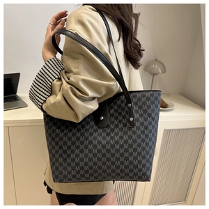 Detailed view of large shoulder tote bag with all-over M letter pattern on a model