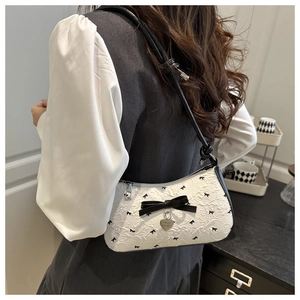 Vue portée du sac porté épaule crème avec nœud noir et pendentif cœur en décor intérieur