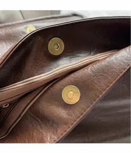 Macro-opname van gouden magneetsluiting op de voering van deze bruine leren tas