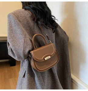 Détail d'un sac selle en cuir marron avec boucle métallique et poignée supérieure