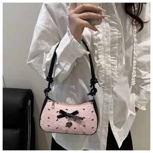 Détail du sac texturé rose avec nœud en soie noire et pendentif en forme de cœur