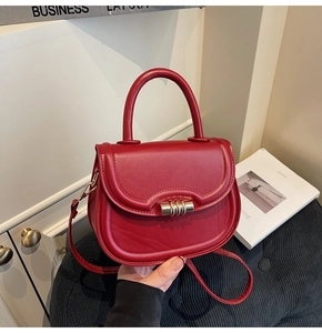 Vue détaillée du sac selle rouge avec fermoir rotatif doré et texture en cuir lisse élégante