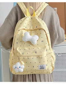 Détail d'un sac à dos jaune à pois avec une peluche étoile mignonne et motifs de nœuds