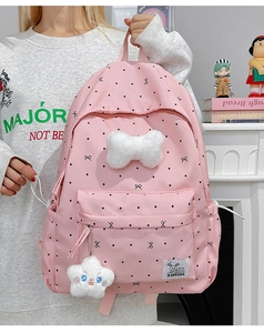 Détail d'un sac à dos rose à pois avec nœud en peluche blanc et pendentif étoile