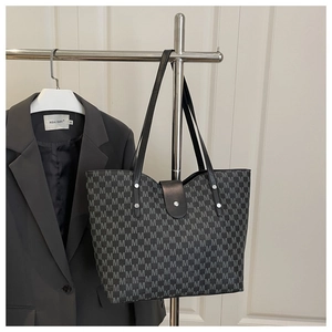 Detail of black tote bag featuring grey M-letter monogram print and long leather strap