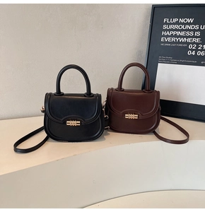 Detail view of mini saddle bags in black and dark brown with elegant gold spiral metal buckles