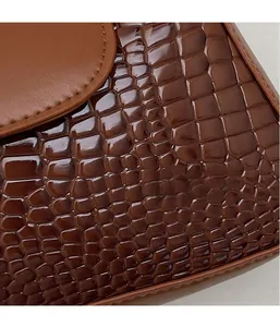 Détail macro du cuir embossé crocodile marron foncé avec finition brillante et couture