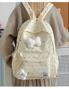 Détail du sac à dos beige à pois avec un grand nœud en peluche et charme d'étoile