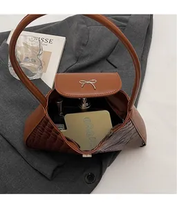 Vue détaillée de l'intérieur spacieux et du nœud argenté du sac marron motif crocodile