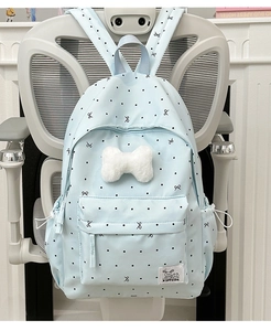 Détail d'un sac à dos bleu clair à pois avec nœud en peluche et poche latérale à cordon