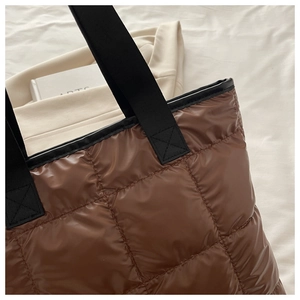 Détail du sac cabas matelassé marron avec coutures renforcées sur les anses noires