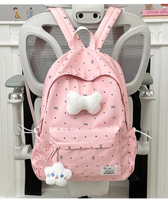 Sac à dos rose à pois avec nœud en peluche et pendentif nuage sur une chaise grise