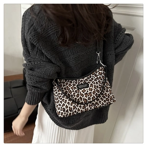 Detalle de bolso de hombro con estampado de leopardo, correa negra y herrajes plateados