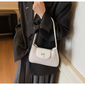 Détail du sac à bandoulière blanc à motif crocodile avec boucle métallique à nœud