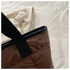 Détail du sac à main matelassé marron avec poignées noires et coutures de précision
