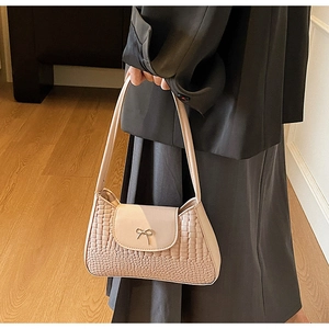 Gros plan sur un sac baguette rose avec gaufrage crocodile et noeud doré chic