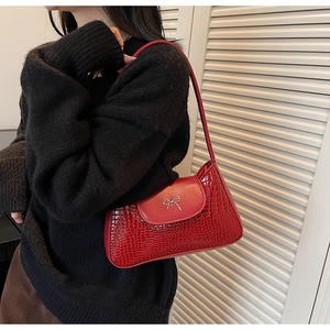 Détail du sac à bandoulière en cuir gaufré crocodile rouge avec nœud argenté