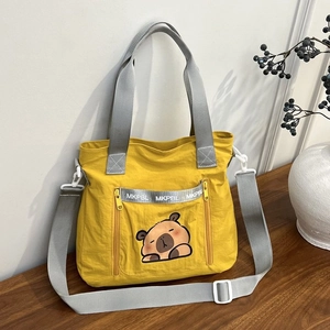 Detail of yellow nylon bucket bag featuring a cute cartoon capybara and silver reflective strip