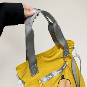 Detail showing yellow nylon tote with grey webbing handles and MKPBL decorative strap