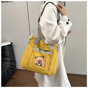 Detail of yellow nylon tote bag featuring cute capybara print and grey webbing handles