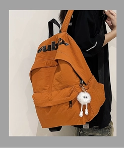 Dettaglio del grande zaino in nylon marrone arancio con tasche laterali e charm in peluche