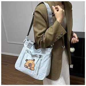 Detail of light blue nylon bag featuring a cute capybara print and multiple zipper pockets