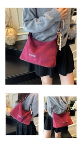 Detail of burgundy matte PU shoulder bag featuring metal logo and ethnic tassel charm