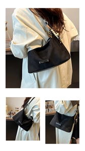 Detail of matte black shoulder bag featuring bohemian bead pendant and metal logo plate
